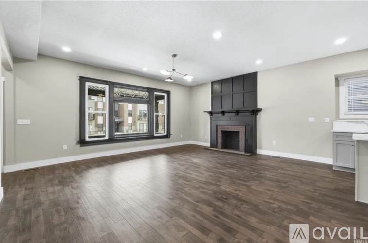 A spacious living room with wood flooring and a fireplace.