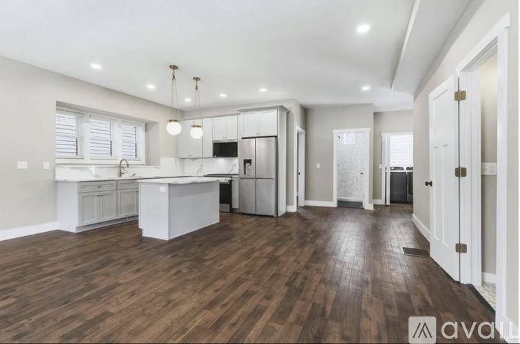 A spacious kitchen with wooden floors and white cabinetry.