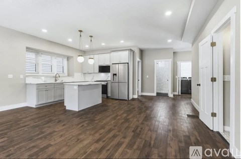 A spacious kitchen with wooden floors and white cabinetry.