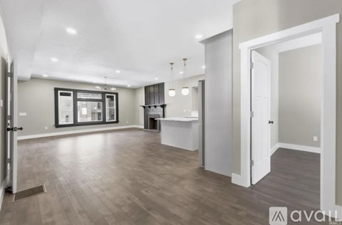 A spacious room with wooden flooring and a large window.