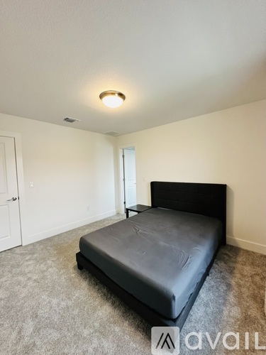 A bedroom with a bed and a carpeted floor.
