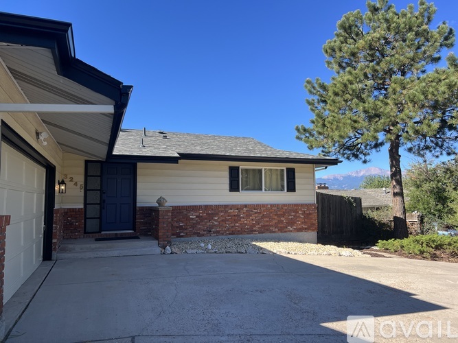 A house with a blue door and a tree in front.