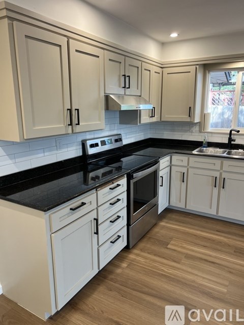 A kitchen with white cabinets and black countertops.