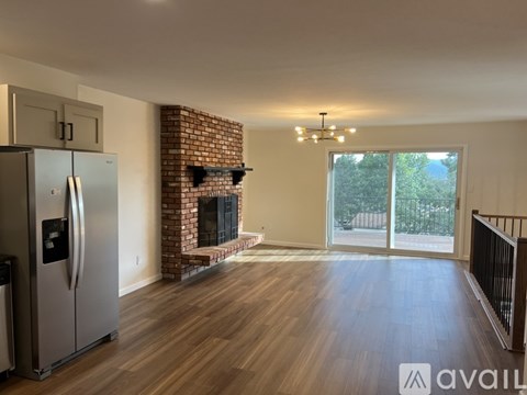 A spacious living room with a brick fireplace and hardwood floors.