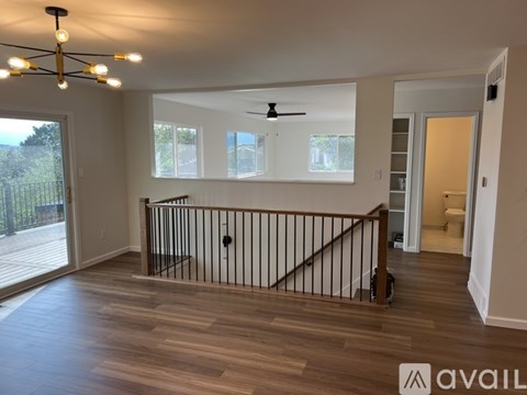 A spacious room with a balcony and a ceiling fan.