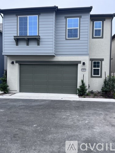 A two-story house with a garage door and a window on the second floor.