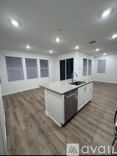 A kitchen with white cabinets and a wooden floor.