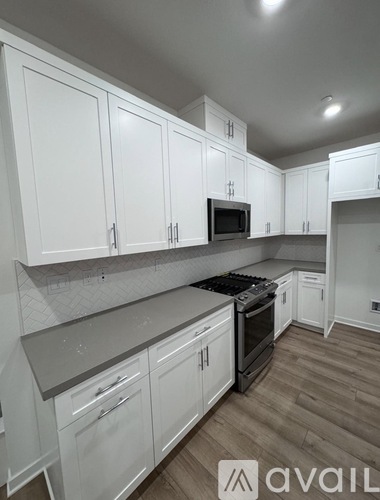 A kitchen with white cabinets and a wooden floor.