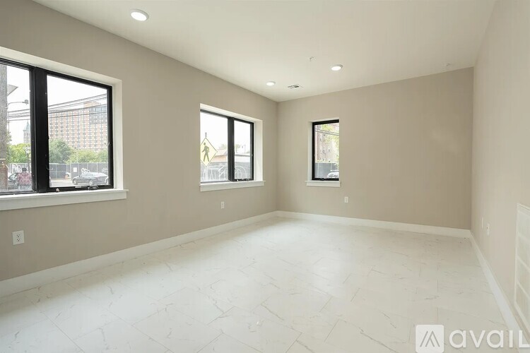 A spacious empty room with two windows and a floor that has a herringbone pattern.