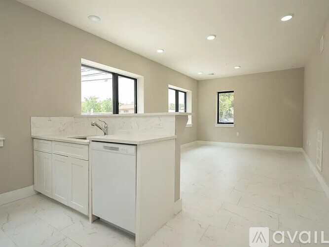 A spacious kitchen with white cabinets and a marble countertop.
