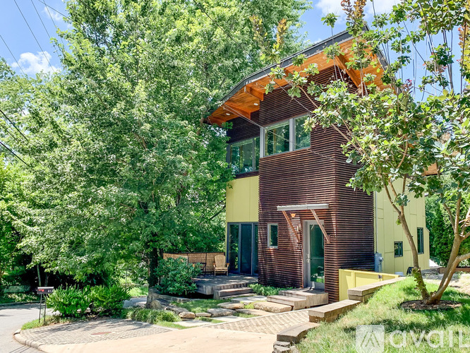 A house with a yellow and brown exterior is surrounded by greenery.