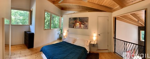 A bedroom with a bed, nightstand, and a painting on the wall.