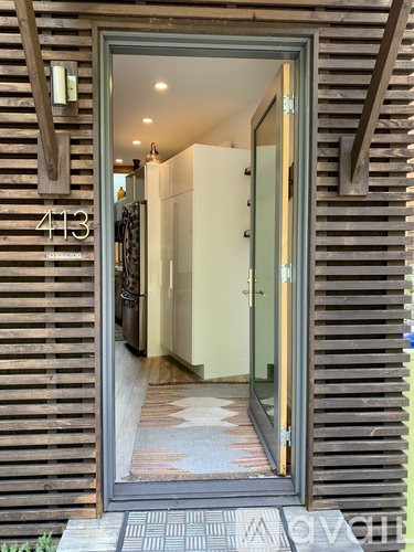 A modern house entrance with a glass door and a number 413 on the wall.