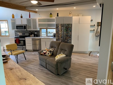 A modern kitchen with a refrigerator covered in magnets and a grey couch with a pillow on it.