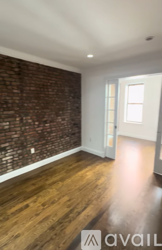 A room with wooden floors and a brick wall.