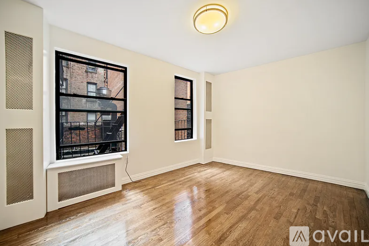 A room with wooden floors and a window with a view of a building outside.