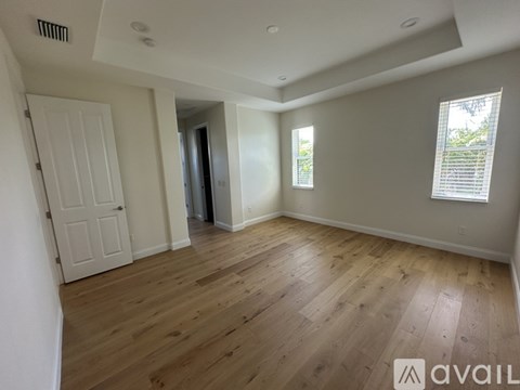 A spacious room with wooden flooring and white walls.