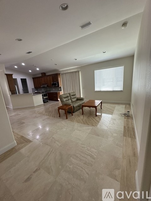 A living room with a wooden chair and a kitchen in the background.