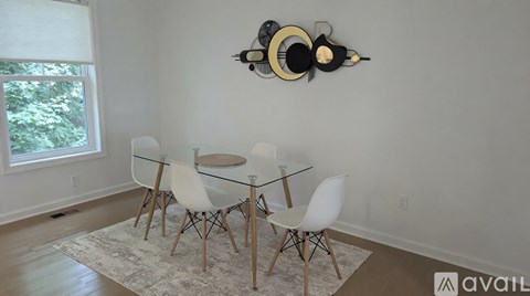 A dining room with a glass table and white chairs.