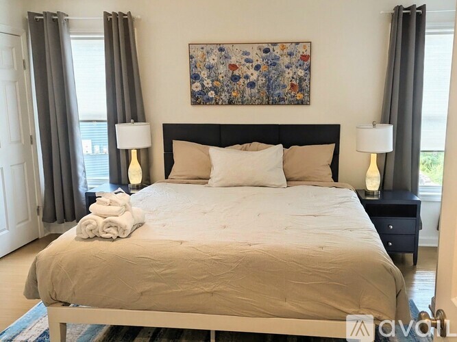 A bedroom with a large bed and a floral painting above it.
