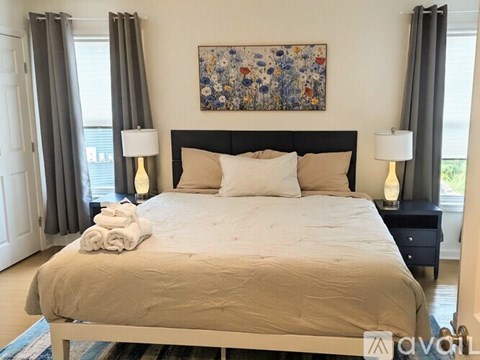 A bedroom with a large bed and a floral painting above it.