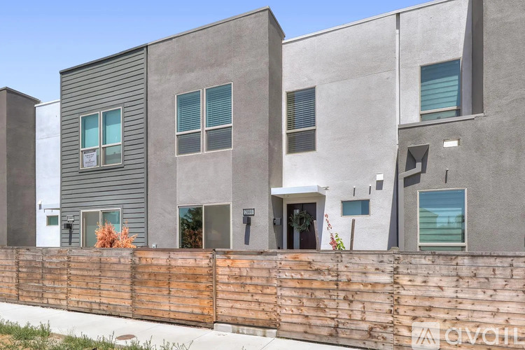 A modern house with a grey exterior and a wooden fence in front.