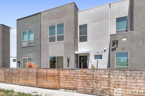 A modern house with a grey exterior and a wooden fence in front.