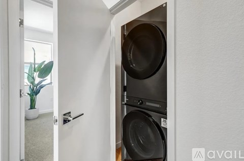 A washing machine is in a small space between a door and a wall.