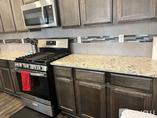 A kitchen with a black stove top oven and a microwave above it.