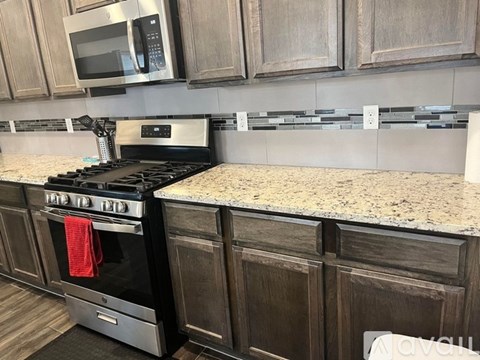 A kitchen with a black stove top oven and a microwave above it.