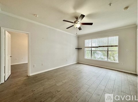 A spacious room with a ceiling fan and wooden flooring.