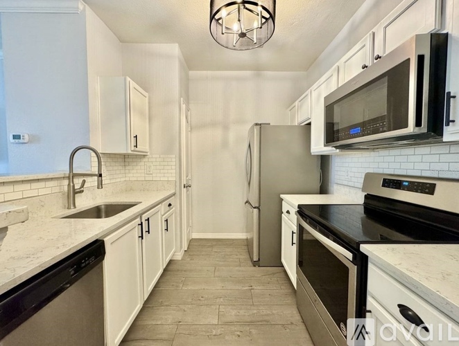 A kitchen with white cabinets and black appliances.