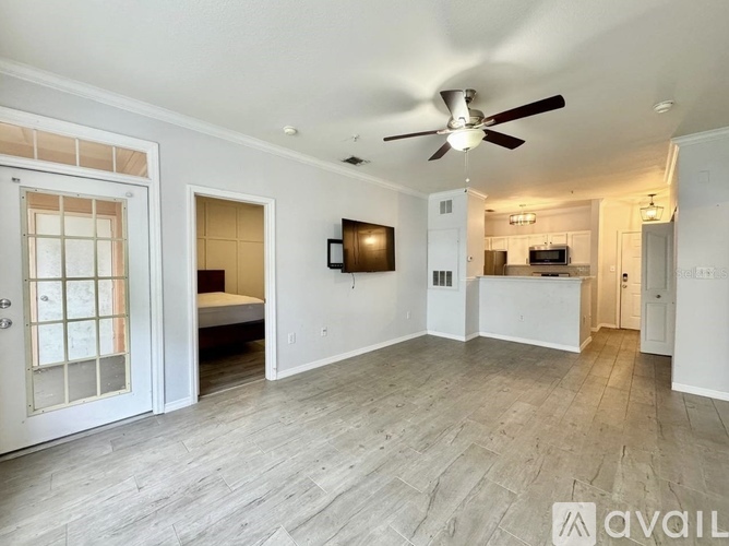 A spacious living room with a ceiling fan and a flat-screen TV.