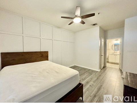 A bedroom with a bed, wooden headboard, and a ceiling fan.