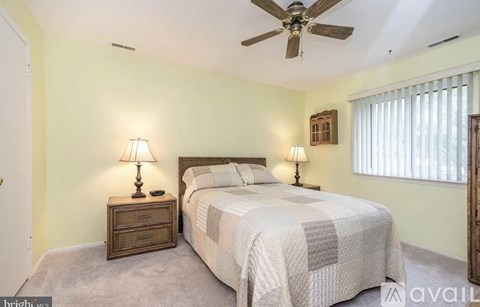 A bedroom with a bed, two lamps, and a ceiling fan.