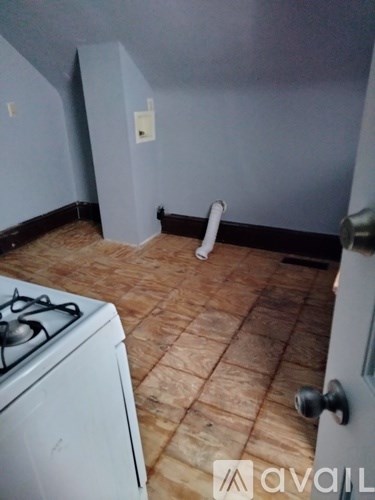 A room with a white gas stove and wooden flooring.