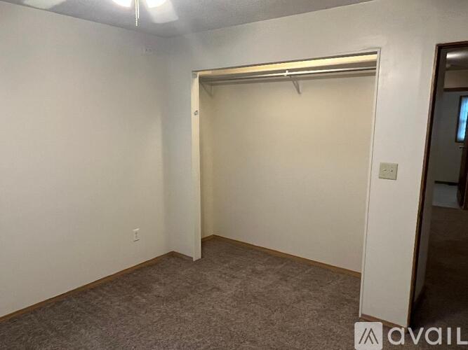 A room with a carpeted floor and a white wall with a doorway leading to another room.