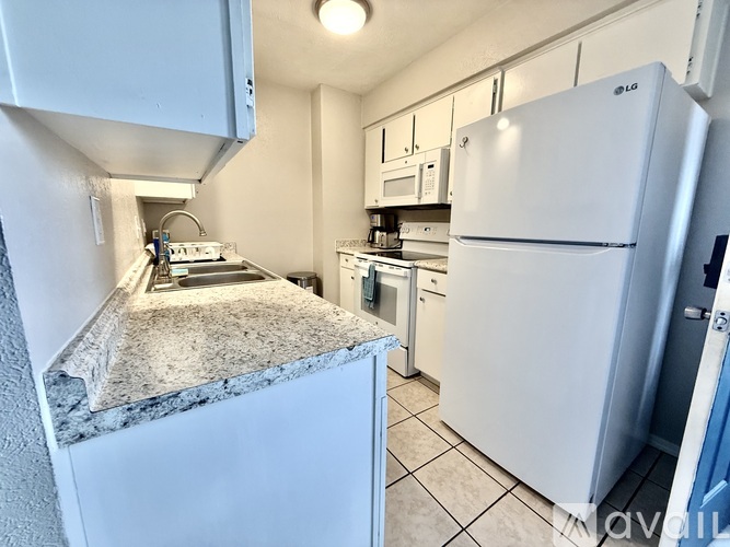 A kitchen with white appliances and a marble counter.