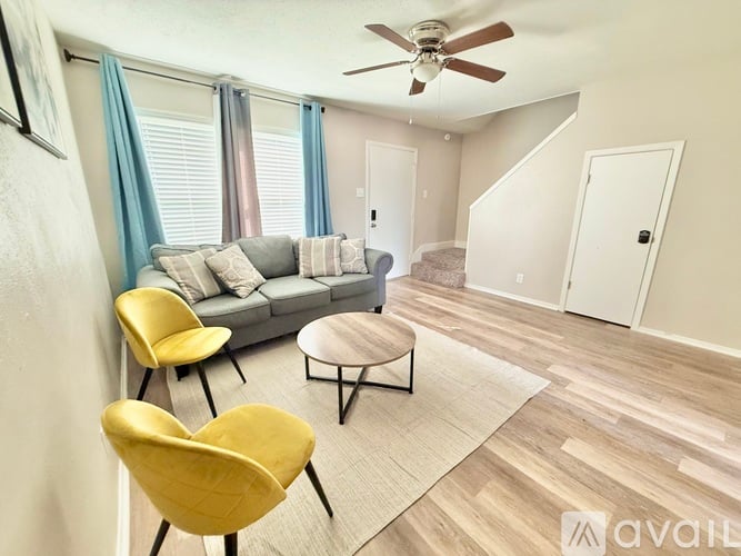A living room with a grey sofa, yellow chairs, and a ceiling fan.