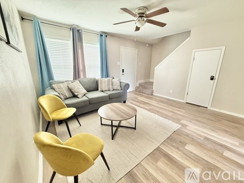A living room with a grey sofa, yellow chairs, and a ceiling fan.