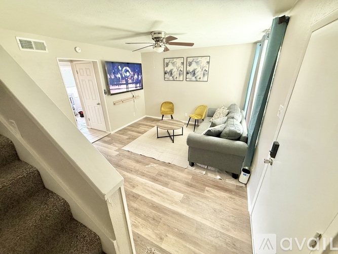 A living room with a couch, chairs, and a television.