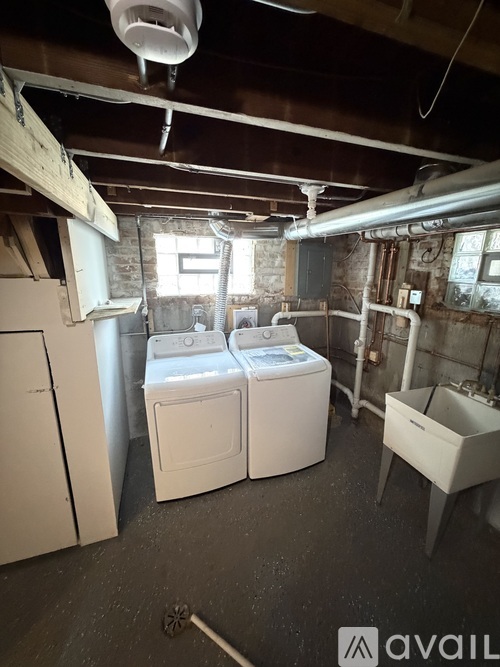 A laundry room with a washer and dryer, sink, and a window.