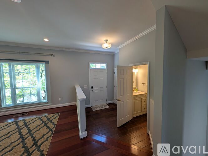 A room with a window, a door, and a rug on the floor.