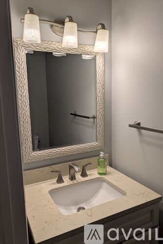A bathroom sink under a mirror with lights above it.