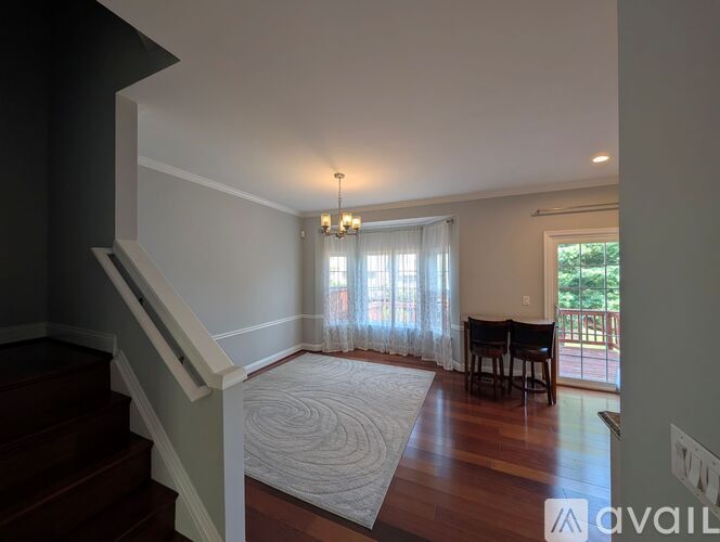 A living room with a staircase on the left and a dining area on the right.