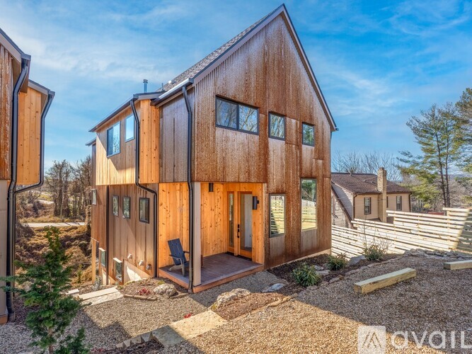 A wooden house with a porch and a gravel area in front.
