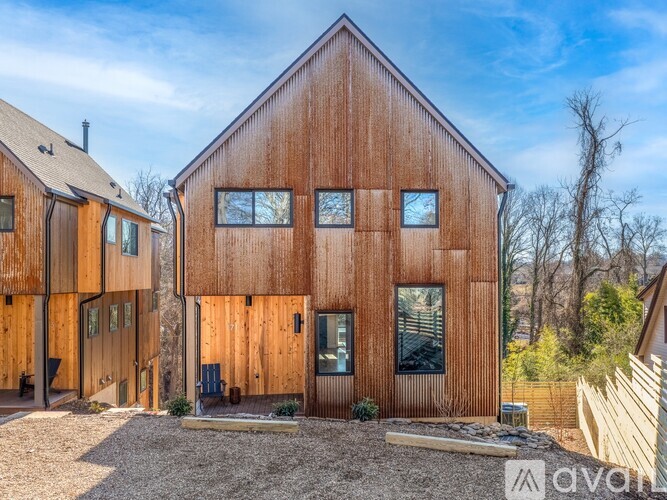 A wooden house with a gravel driveway in front.