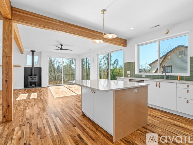 A modern kitchen with wooden floors and white cabinets.