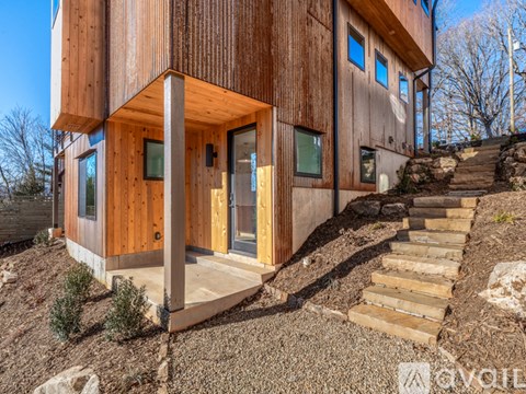 A modern house with wooden exterior and a stone staircase leading up to the entrance.