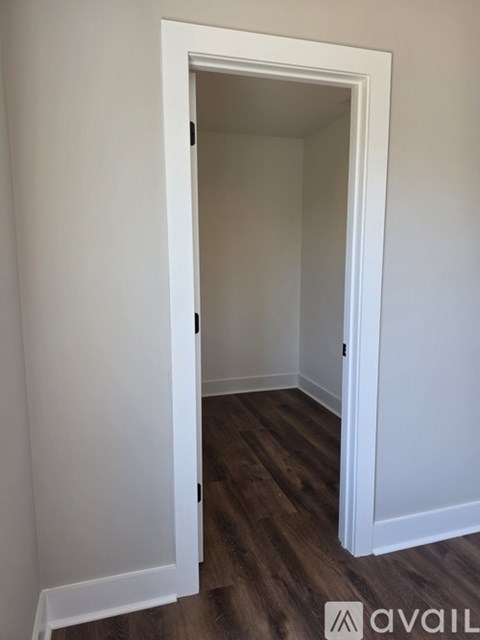 A white door is open to a room with wood flooring.